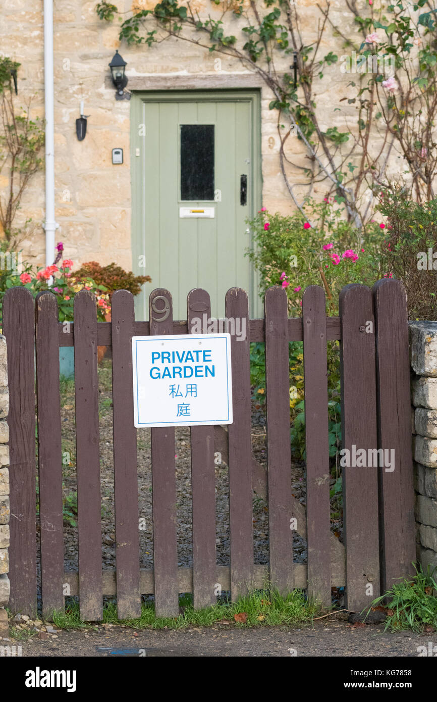 Bibury tourism - 'Private Garden' sign on garden gate written in English and Japanese - Bibury, Gloucestershire, England, UK Stock Photo