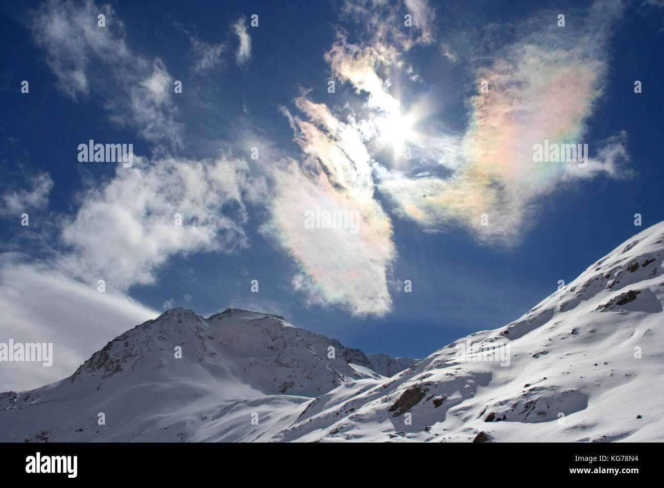Winter landscape in Austria with colorful cirrus clouds around the sun. Stock Photo