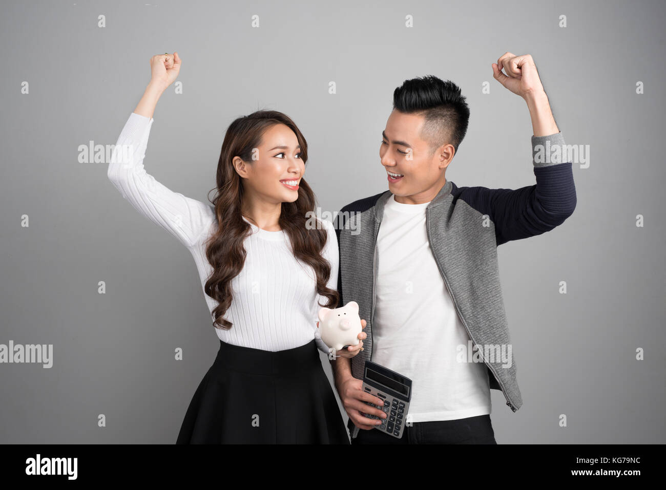 Happy young couple hold pink pig bank and calculator Stock Photo