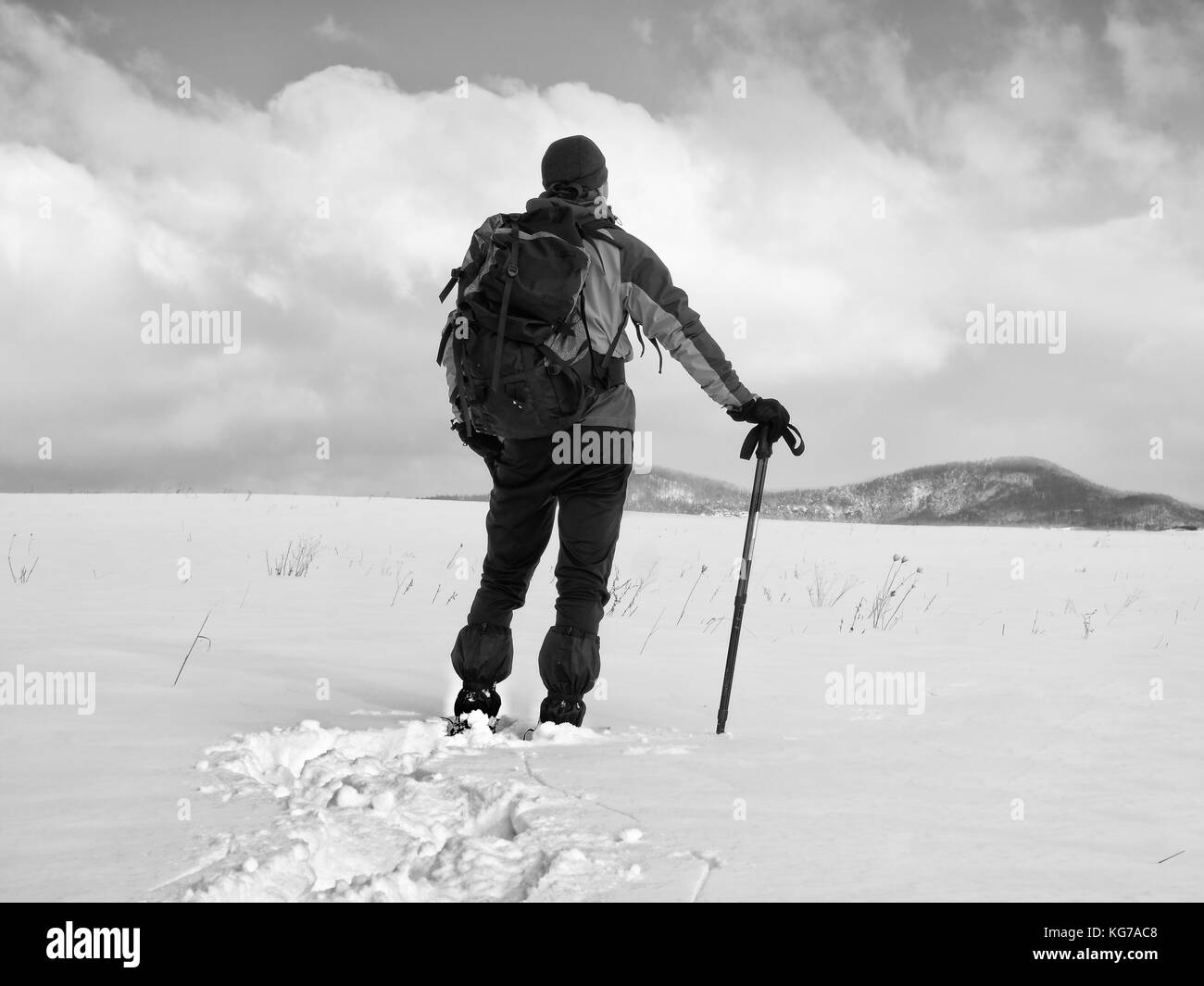 Hiker with backpack snowshoeing in deep drift. Man with snowshoes walk