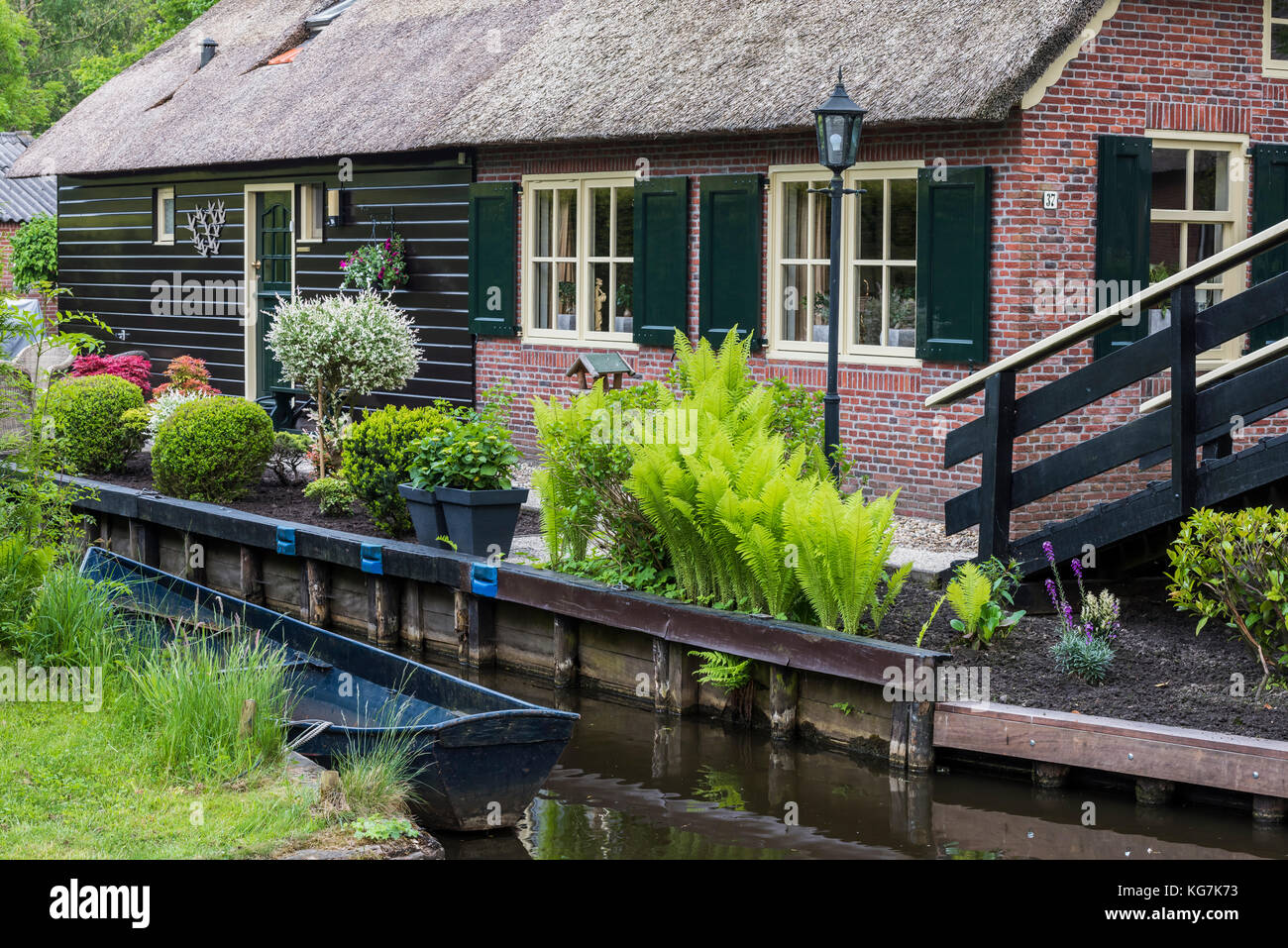 Giethoorn, The Netherlands - May 19., 2016:  Front of a monumental house in the small, picturesque town of Giethoorn with canal and rowing boat, Overi Stock Photo
