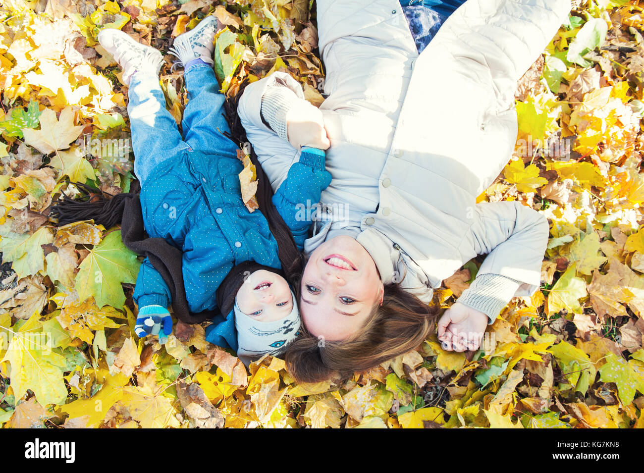 Young mother and her toddler girl have fun in autumn - lying in yellow ...