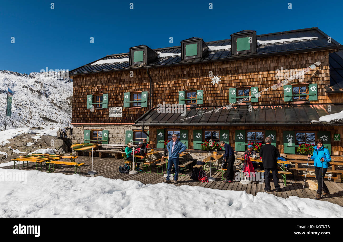 Wildgerlostal, Austria - September 27, 2017: tourists and hikers at the Zittauer Hutte with snow and a great wooden cabin and restaurant, with people  Stock Photo