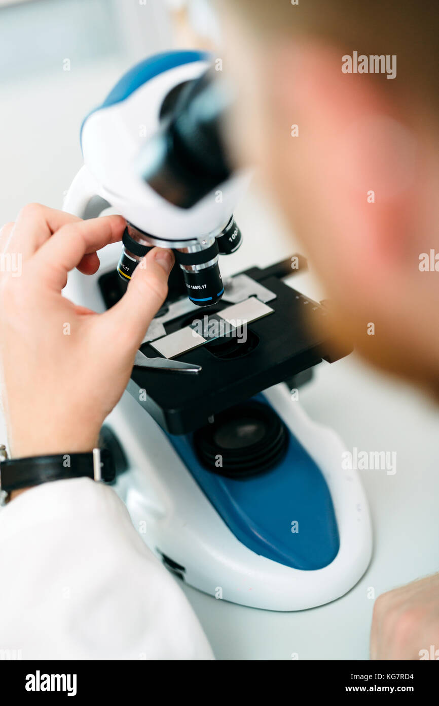 Closeup picture of researcher looking through microscope Stock Photo