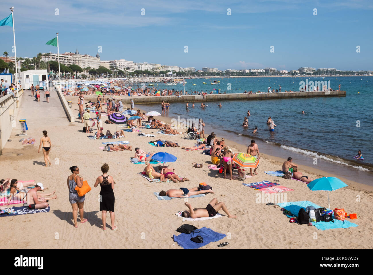 People enjoying sunbathing and swimming at beach along Boulevard de la Croisette, Cannes, Cote d'Azur, Provence-Alpes-Cote d'Azur, France. Stock Photo
