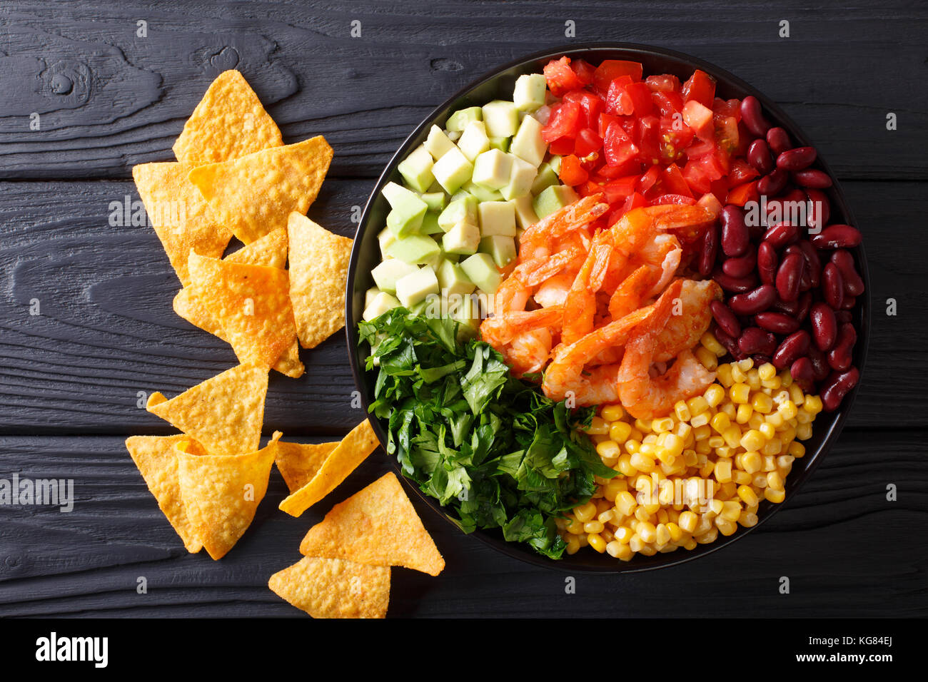 Mexican burrito bowl with shrimp, beans, corn, avocado and herbs closeup on the table. horizontal top view from above Stock Photo