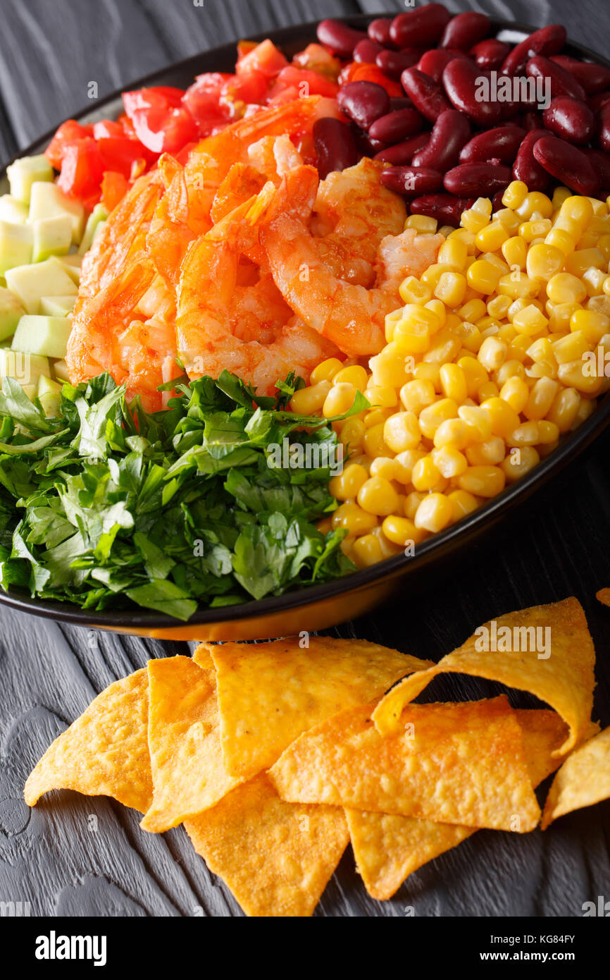 Mexican burrito bowl with shrimp, beans, corn, avocado and herbs closeup on the table. vertical Stock Photo