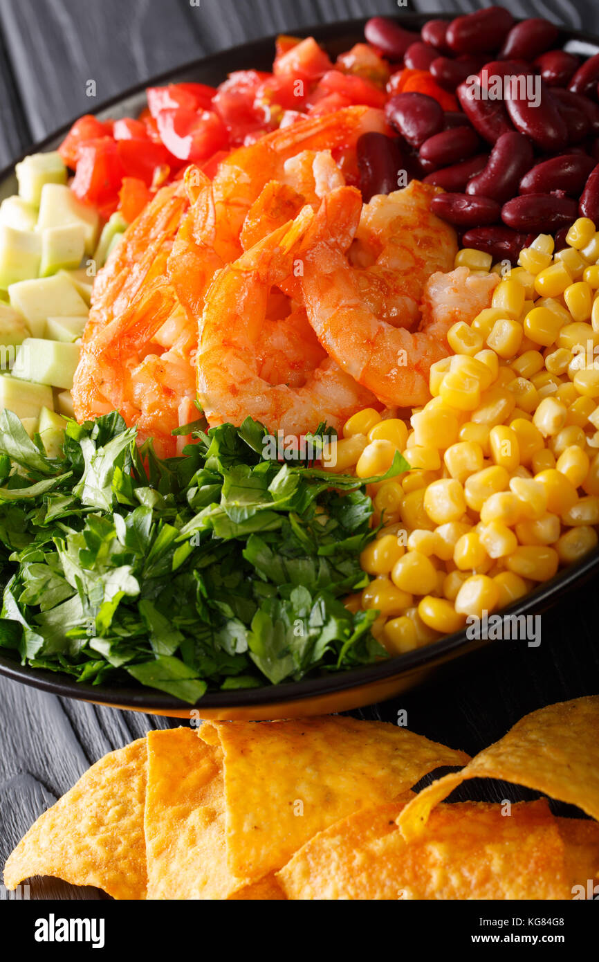 Mexican salad with shrimps, beans, corn, avocado and greens close-up on the table. vertical Stock Photo