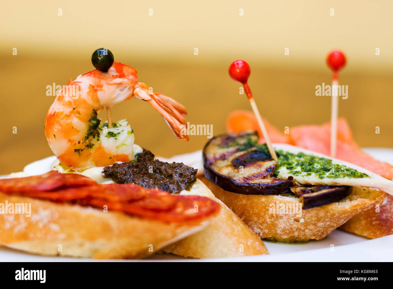 Traditional Spanish Cuisine snacks. Tapas baguette canape with chorizo sausages, black olives, grilled eggplant, salmon and marinated shrimp Stock Photo