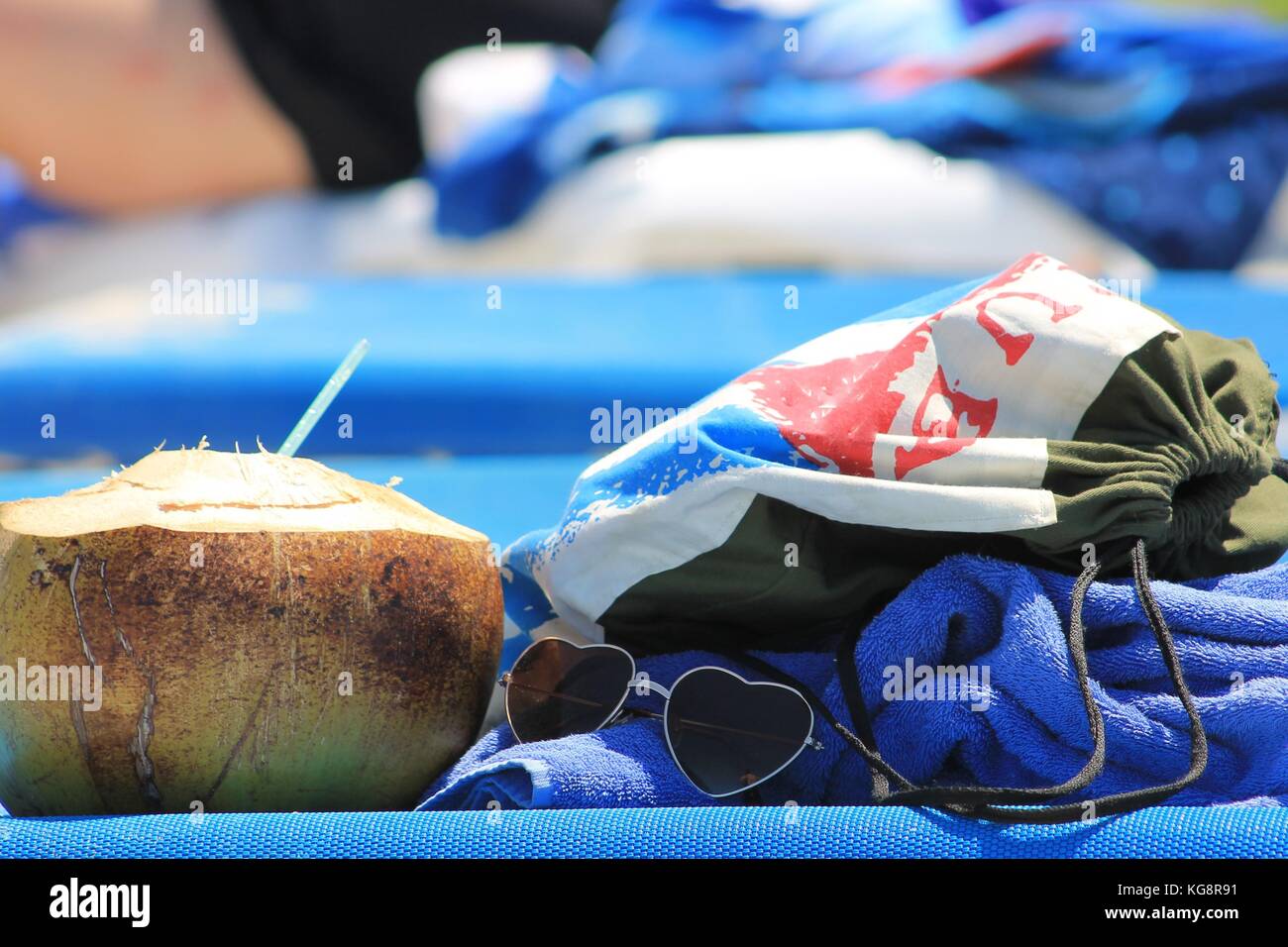 Cuban Beach Day Accessories on beach chair: coconut with straw, heart shaped sunglasses, Cuba beach bag, and beach towel Stock Photo