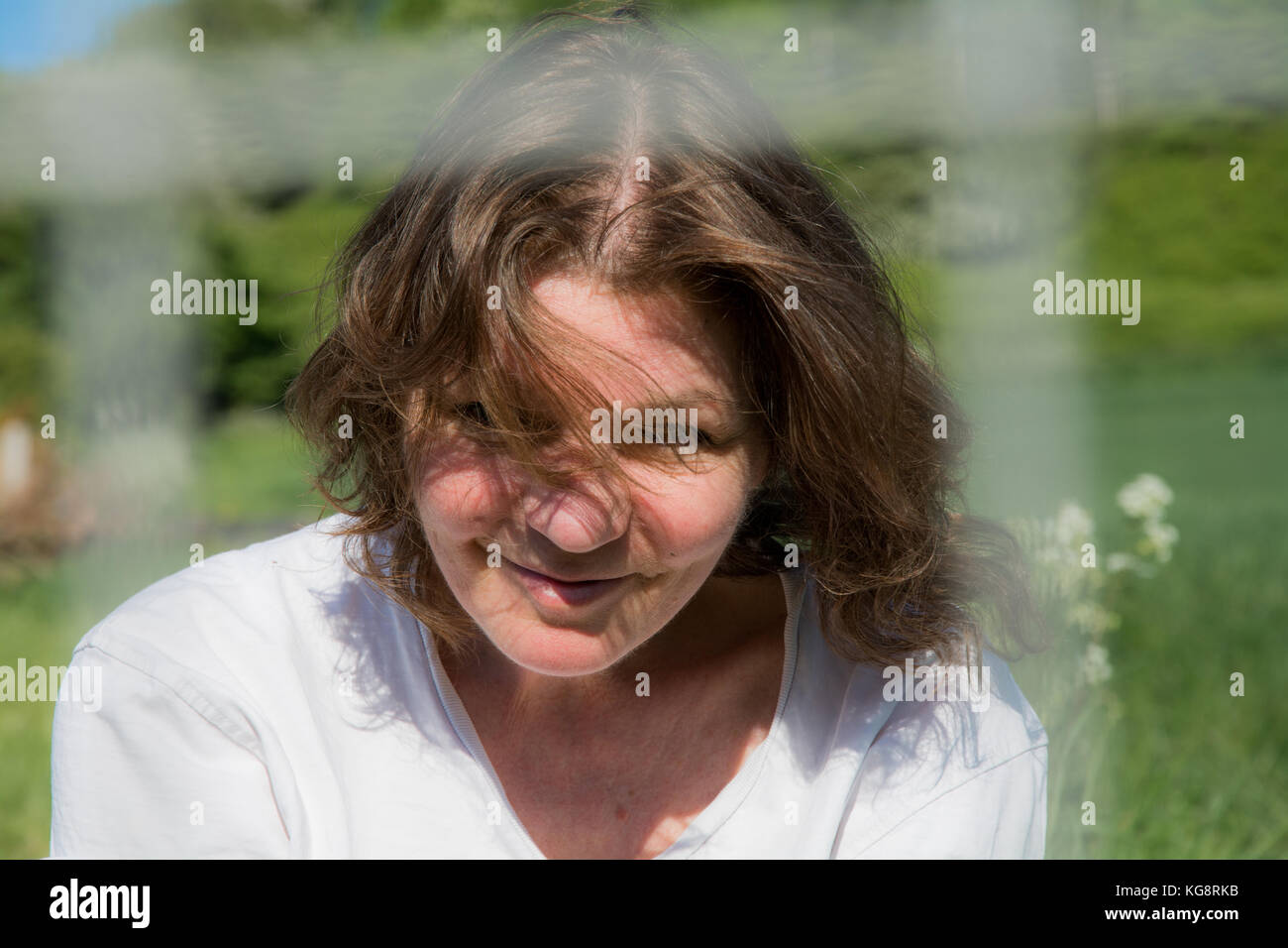 Candid portrait of a beautiful brunette, middle aged woman  - summer breeze blowing in her hair. Much Wenlock, Shropshire, UK Stock Photo
