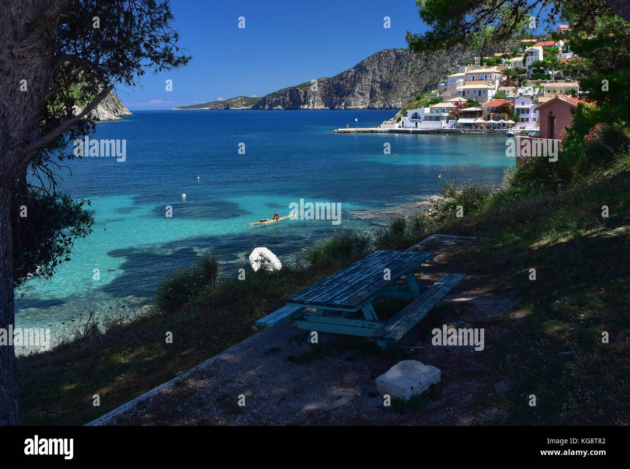 A picnic bench in the shade overlooking the bay at Asos, Cephalonia, Greece. Stock Photo