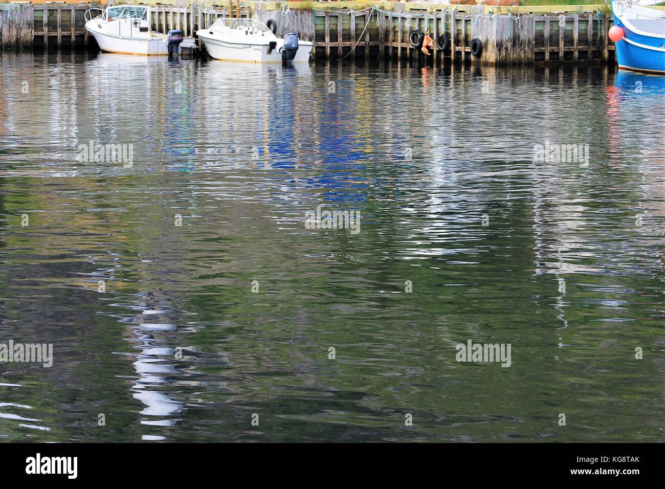 Boats tied up at the pier, Petty Harbour, Newfoundland Labrador. Image mostly of waters surface with boats and pier at top of image. Stock Photo