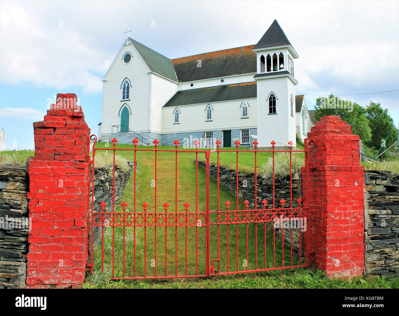 Old St. George's Church, Brigus, Newfoundland and Labrador. Looking from outside of red brick gate posts and iron gate, grass covered footpath. Stock Photo