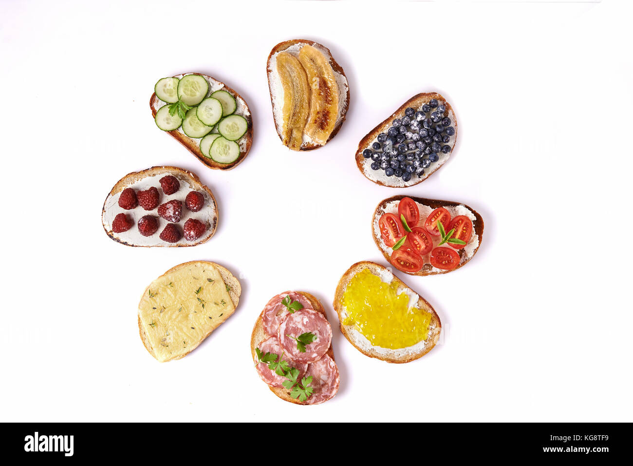 sweet and savory toast isoletd on white background. cheese, cucumber, tomatoes, salami, banana, strawberries, blueberries and fruits jam Stock Photo