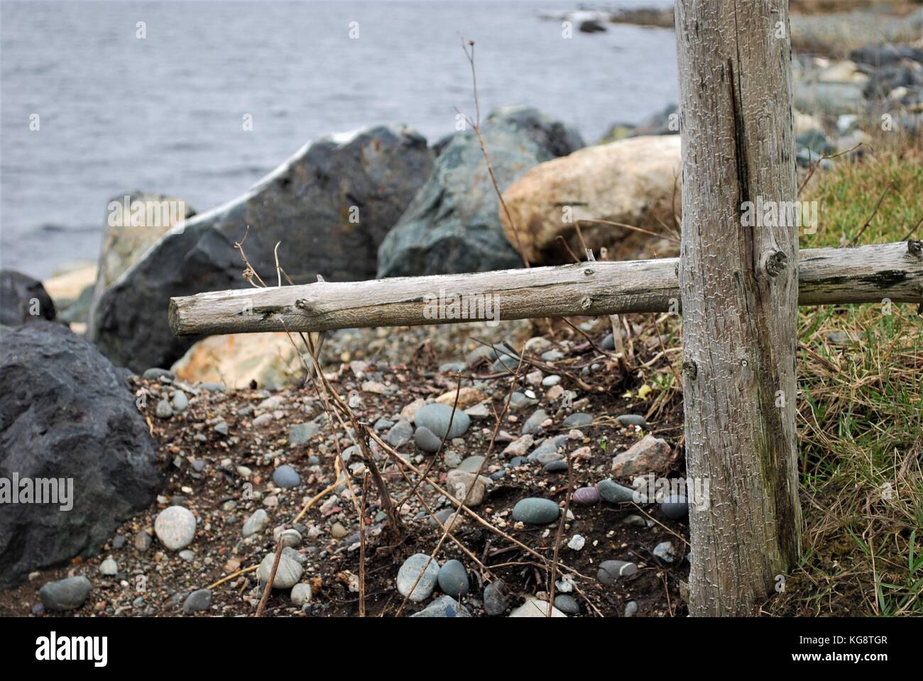 End of fence, fence post and rail. Fence ends just before beach. Some beach and ocean in frame. Stock Photo