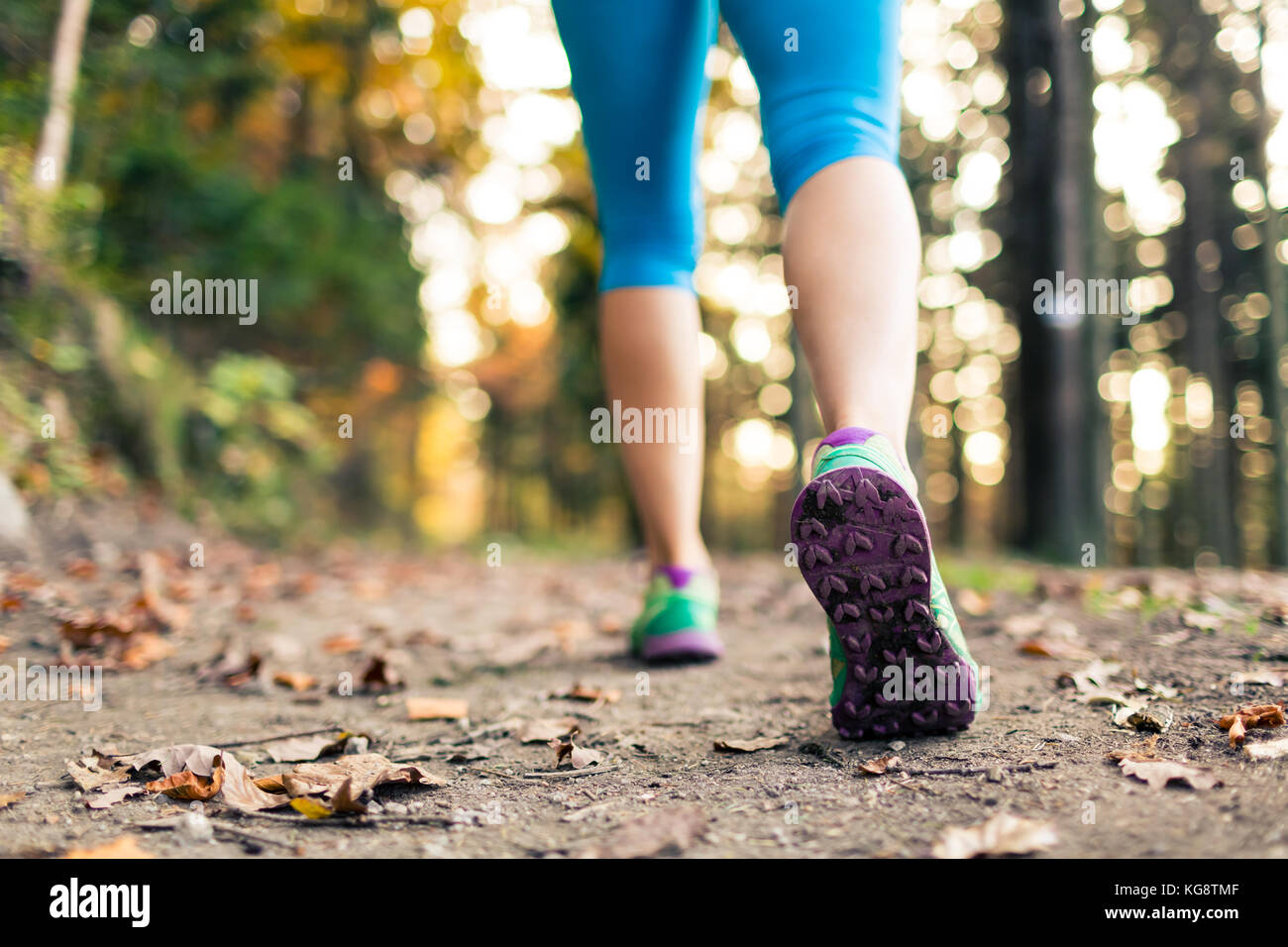 Woman walking and hiking in autumn forest, sport shoes. Jogging, trekking or training outside in autumn nature. Inspiring health and fitness concept. Stock Photo