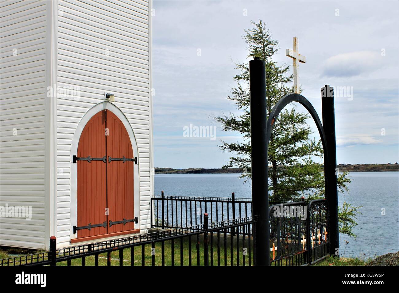 Iron gate and fence around churchyard, and old, wooden church, bay side