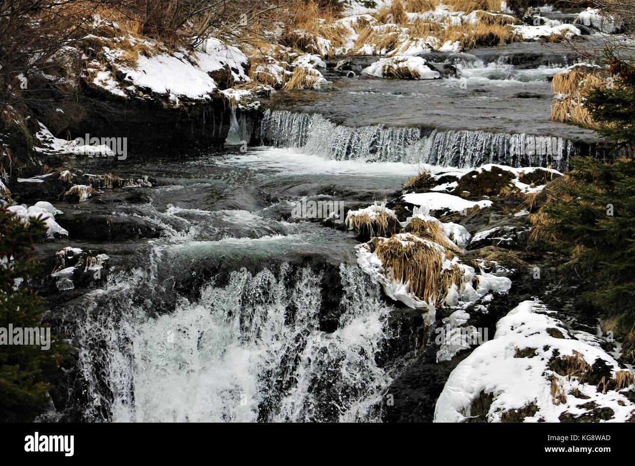 Three small waterfalls on the Virginia River, St. John's, Newfoundland, Canada. Snow on the river banks. Water is grey and cold looking Stock Photo