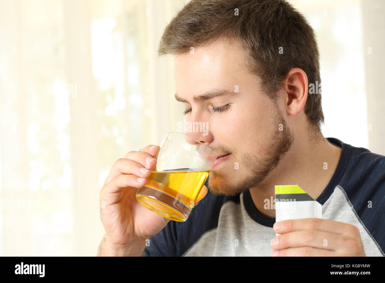 Man drinking an orange liquid medicine in a house interior Stock Photo
