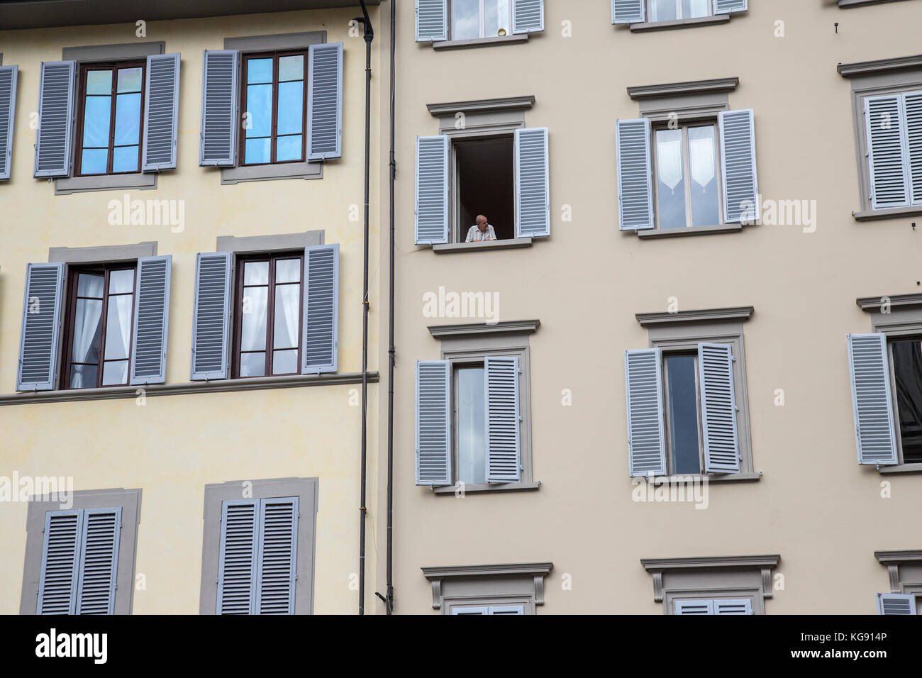 Florentine apartment scene showing louvred windows with an elderly gentleman looking out of one Stock Photo