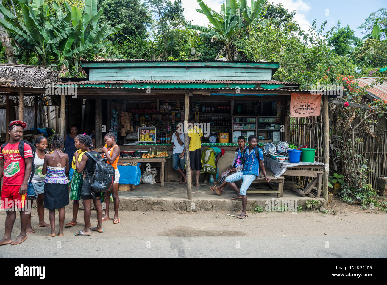Young Malagasy men and women gather in front of a convenience store. Madagascar, Africa. Stock Photo