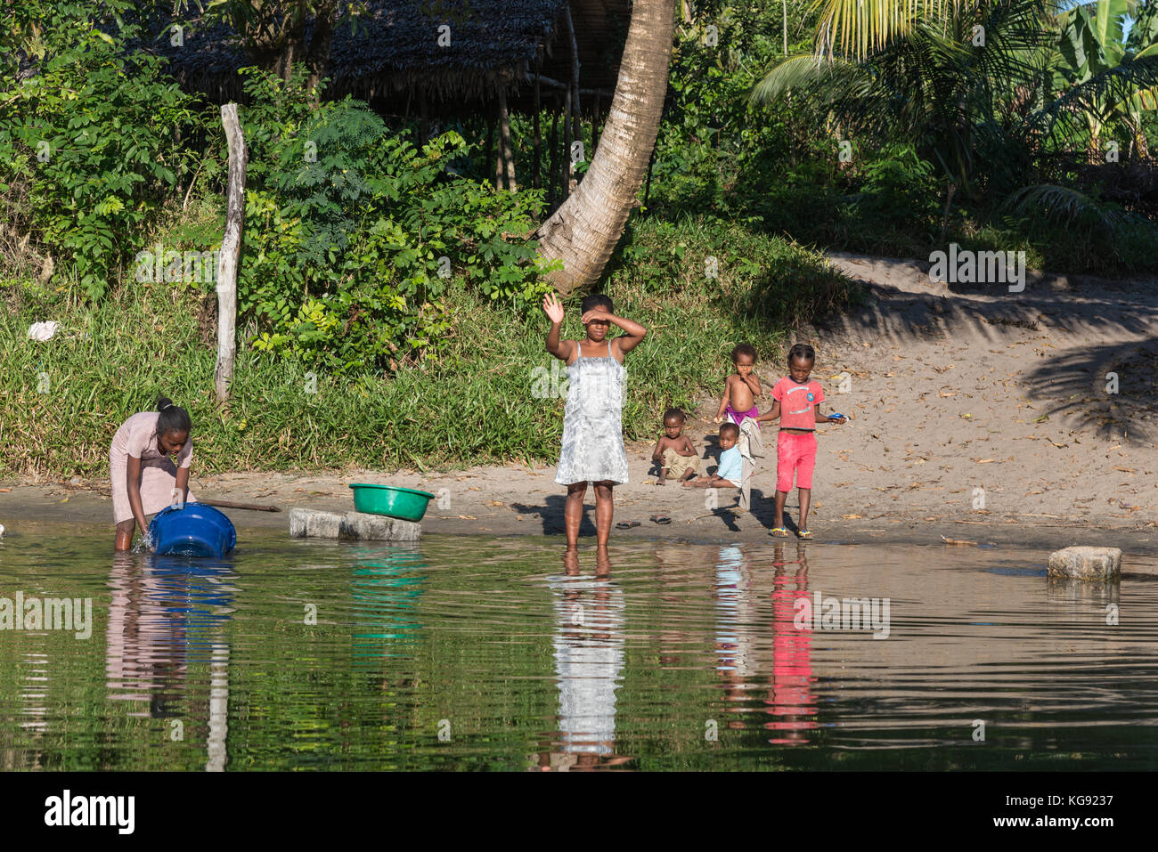 Malagasy women and children wash and clean by a river. Madagascar, Africa. Stock Photo