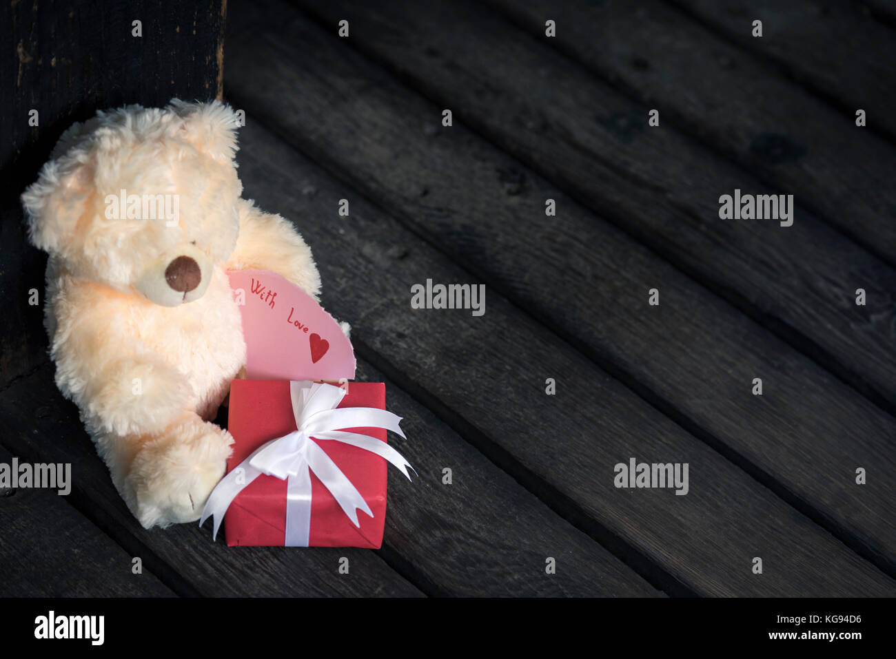 Red gift box with white tied bow and a cute teddy bear toy holding a ...
