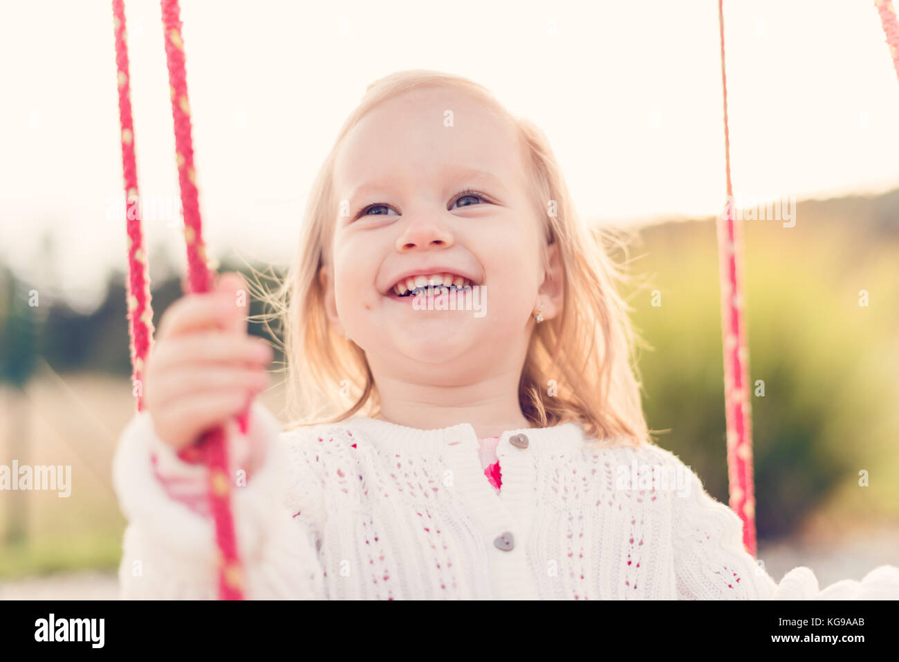 Little girl swinging on a playground. Childhood, Freedom, Happy, Summer Outdoor Concept Stock Photo