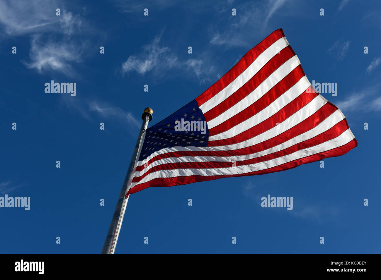 The American Flag Flying, Stars and Stripes,  United states of America Flag Blue sky. The Star-Spangled Banner USA Flag blowing in the wind. Stock Photo