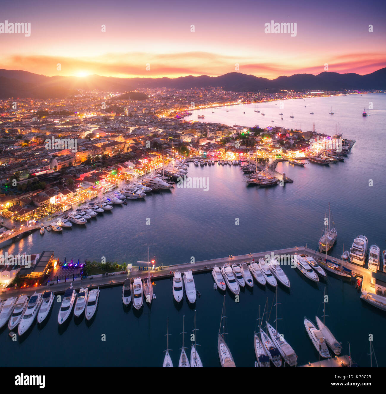 Aerial view of boats and beautiful city at sunset in Marmaris, Turkey. Amazing landscape with boats in marina bay, sea, city lights, mountains, sky, c Stock Photo