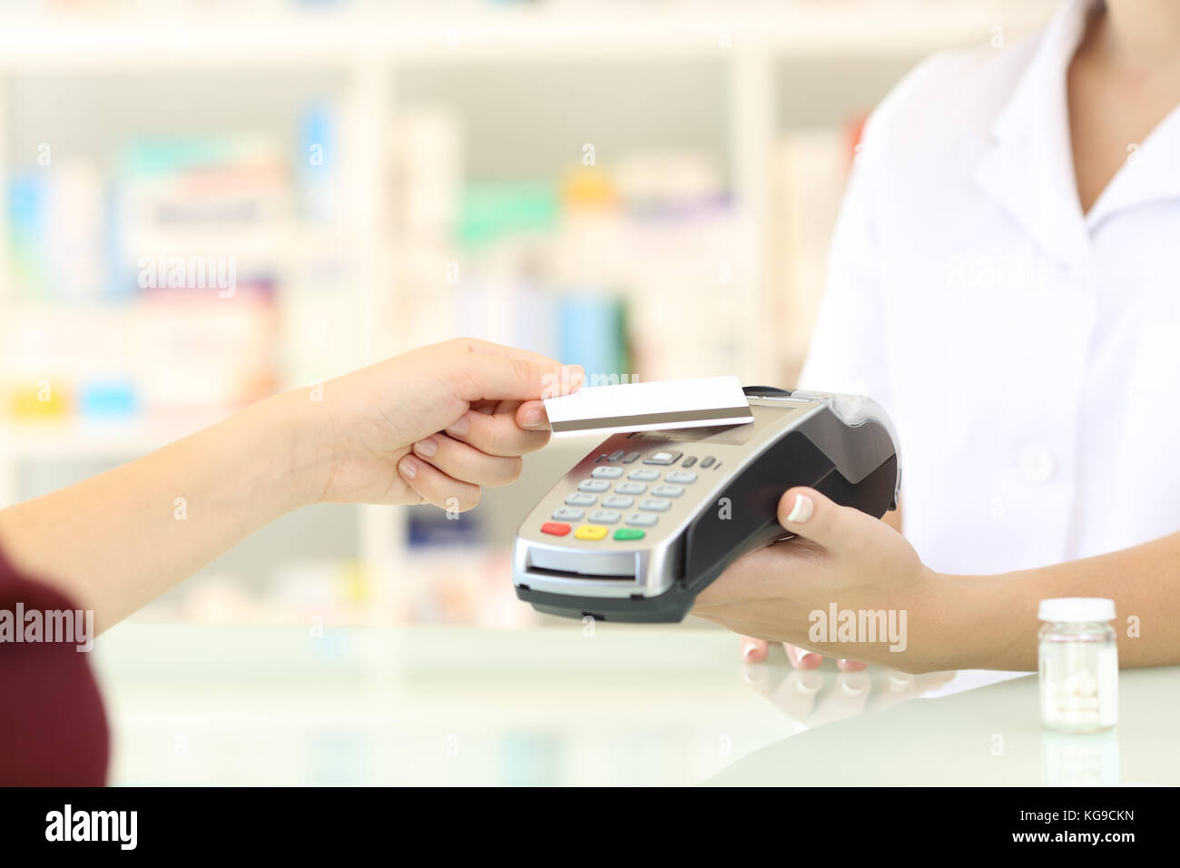 Close up of a customer hands paying with credit card reader in a pharmacy Stock Photo