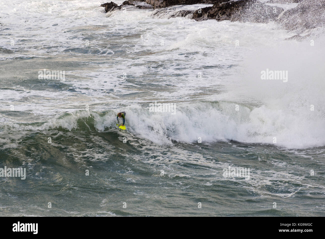 Young surfer riding a wave in rough sea, Port Gaverne, Port Isaac, Cornwall, UK, 5th November 2017. Stock Photo