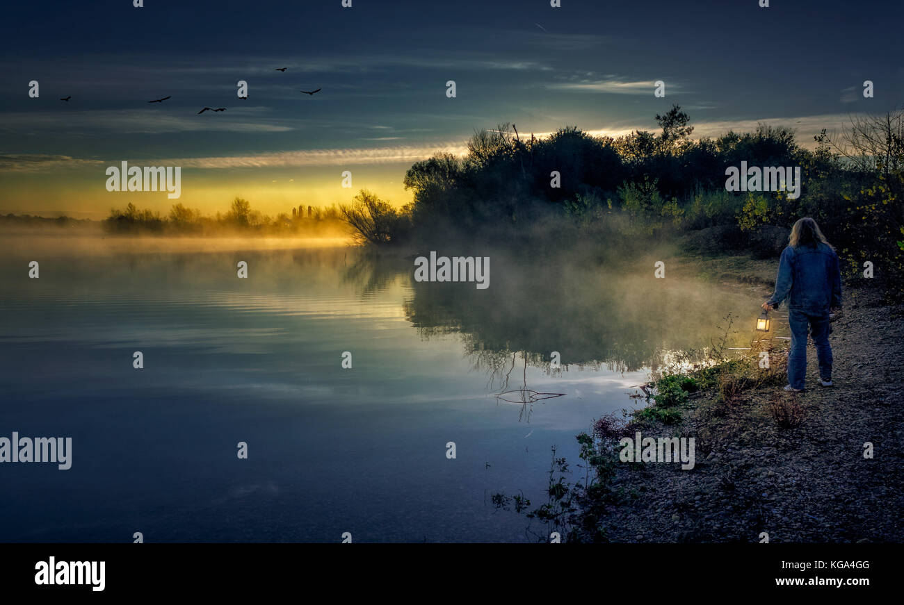 Enjoying the mysterious view at lake on a foggy misty morning Stock Photo