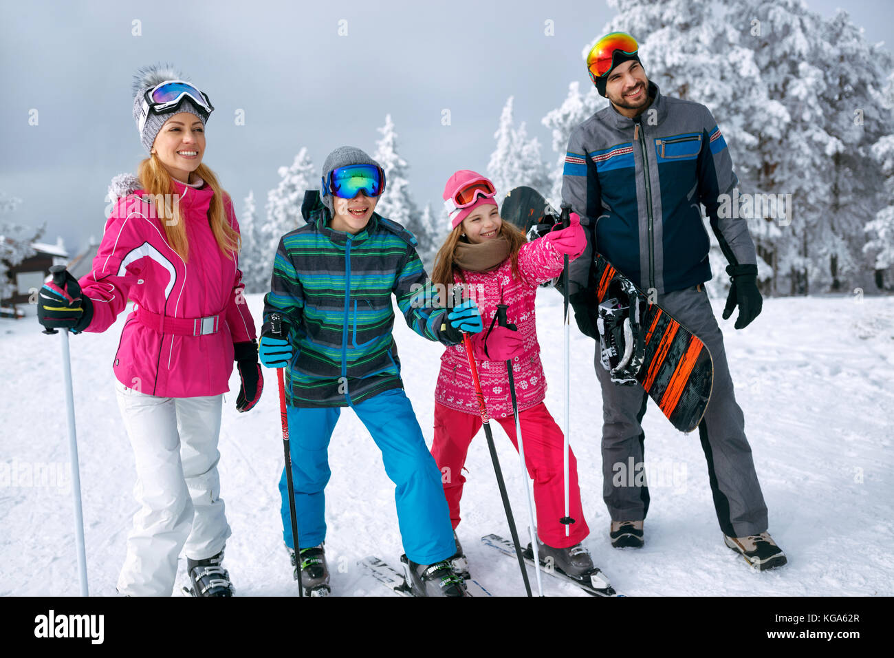 smiling happy family with ski and snowboard on ski holiday in mountains Stock Photo
