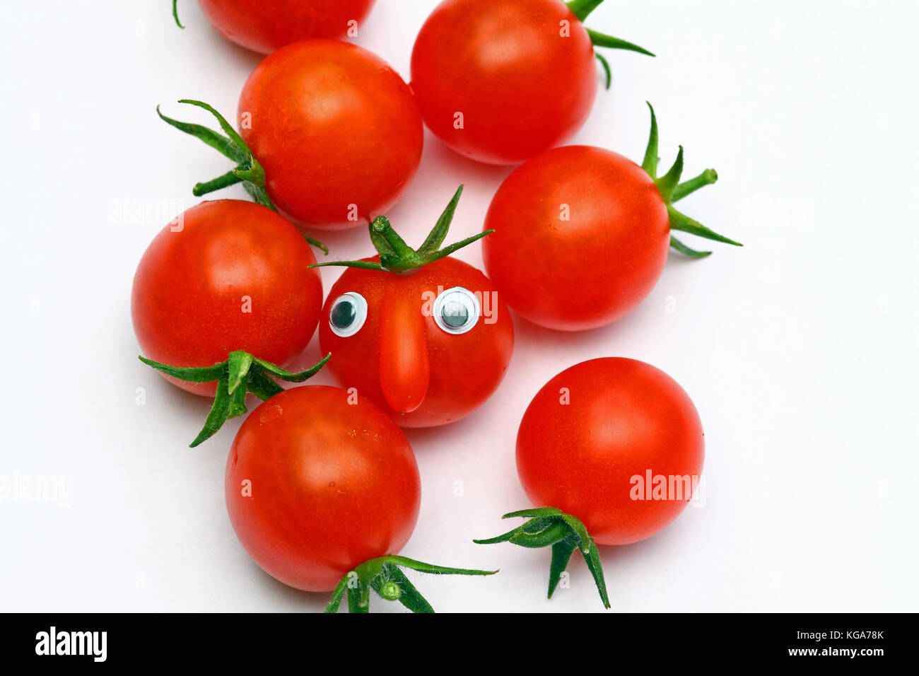Fresh ripe cherry tomato with a face on a plain background with copy space Stock Photo