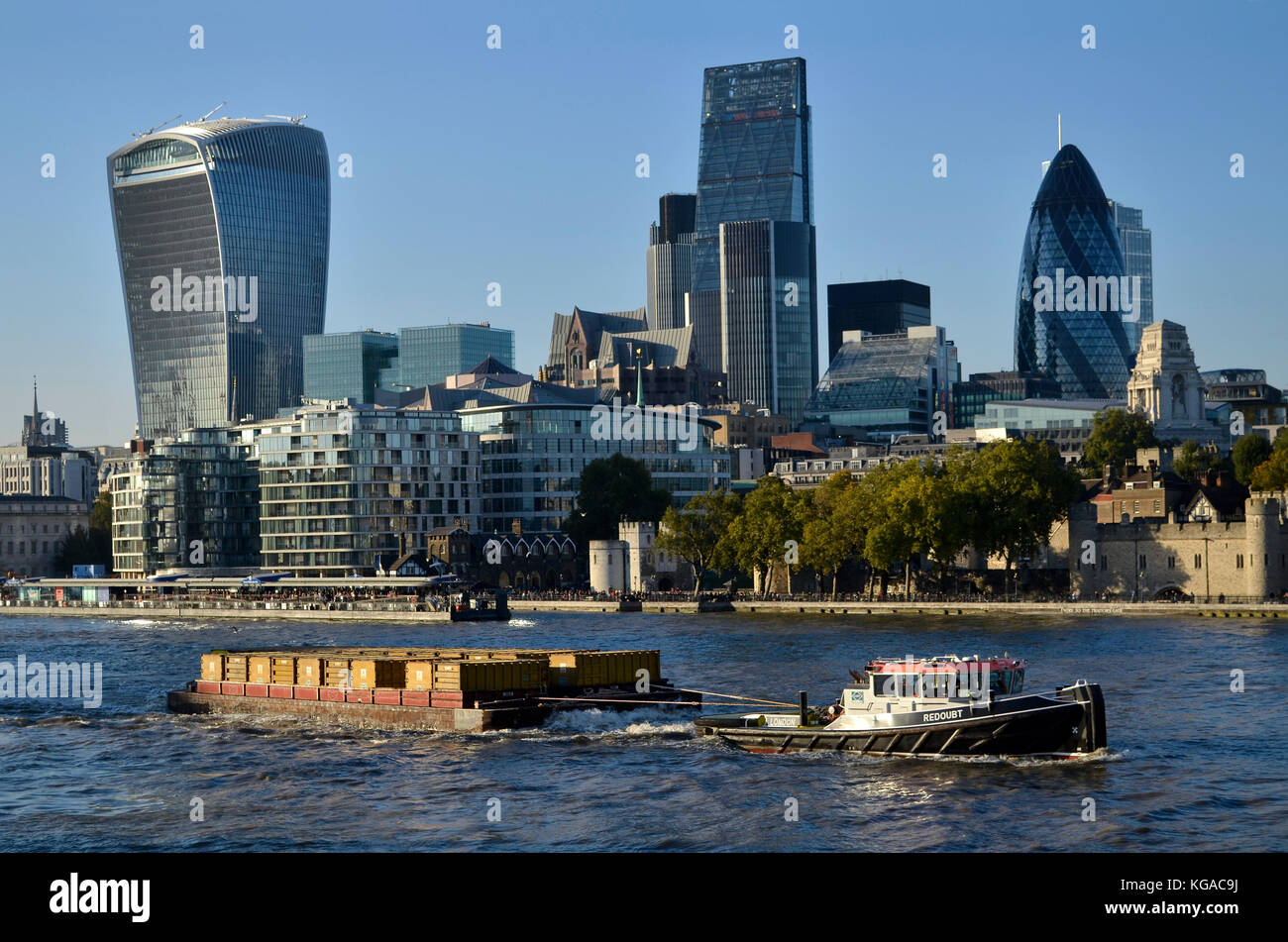 Cory Envirnomental container barge being pulled by tug boat Redoubt, River Thames, London, UK, with London financial district behind. Stock Photo