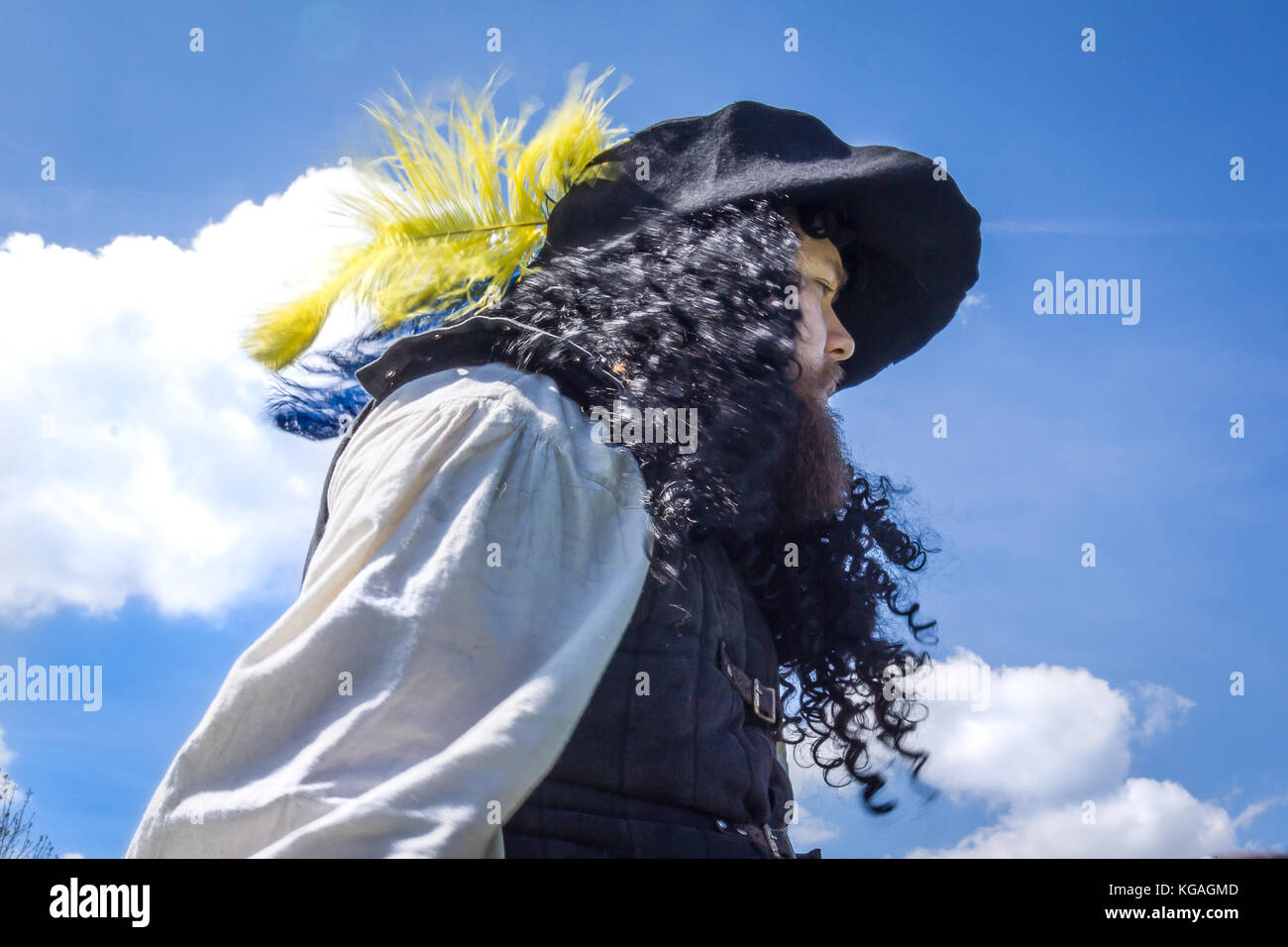 Musketeer with a wide hat and long curly hair against blue sky, Denmark, May 21, 2017 Stock Photo