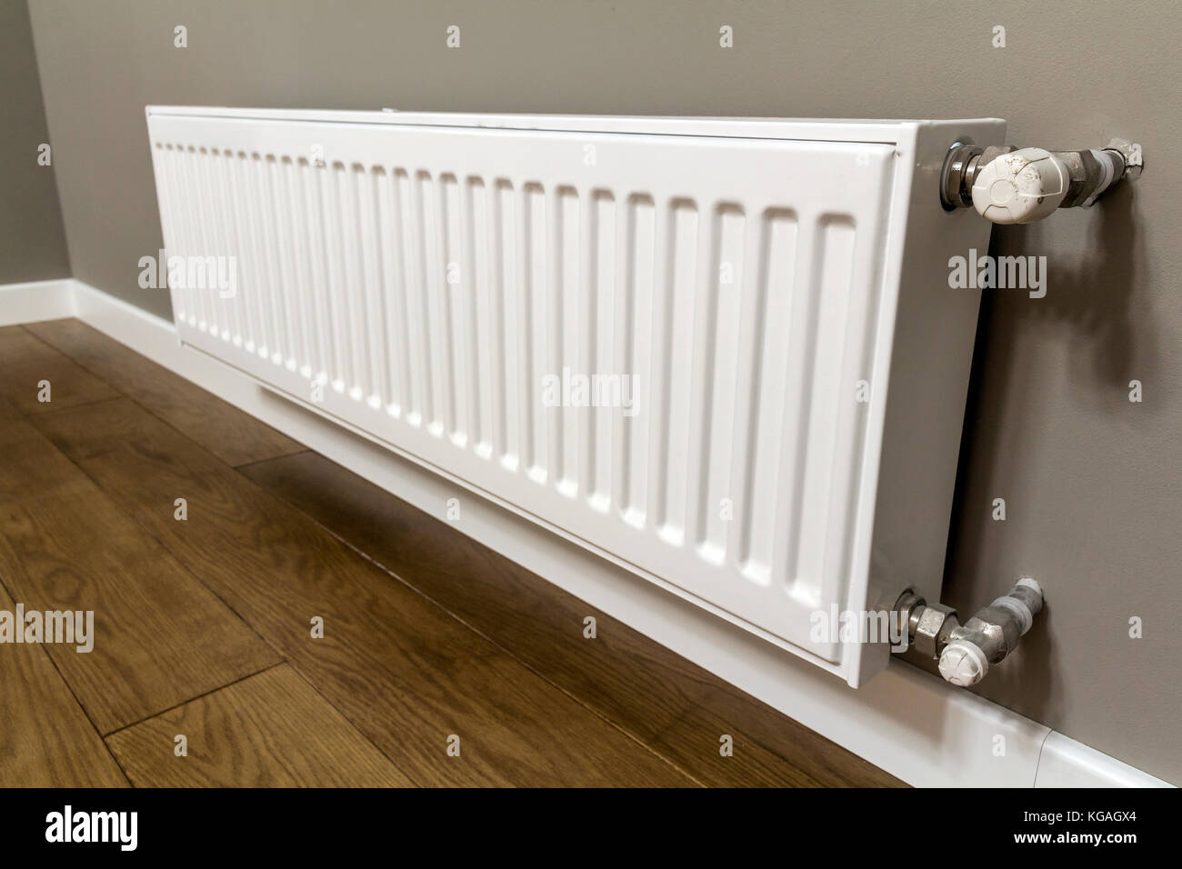 White Heating Radiator On Wall In An Apartment With Wooden Floor
