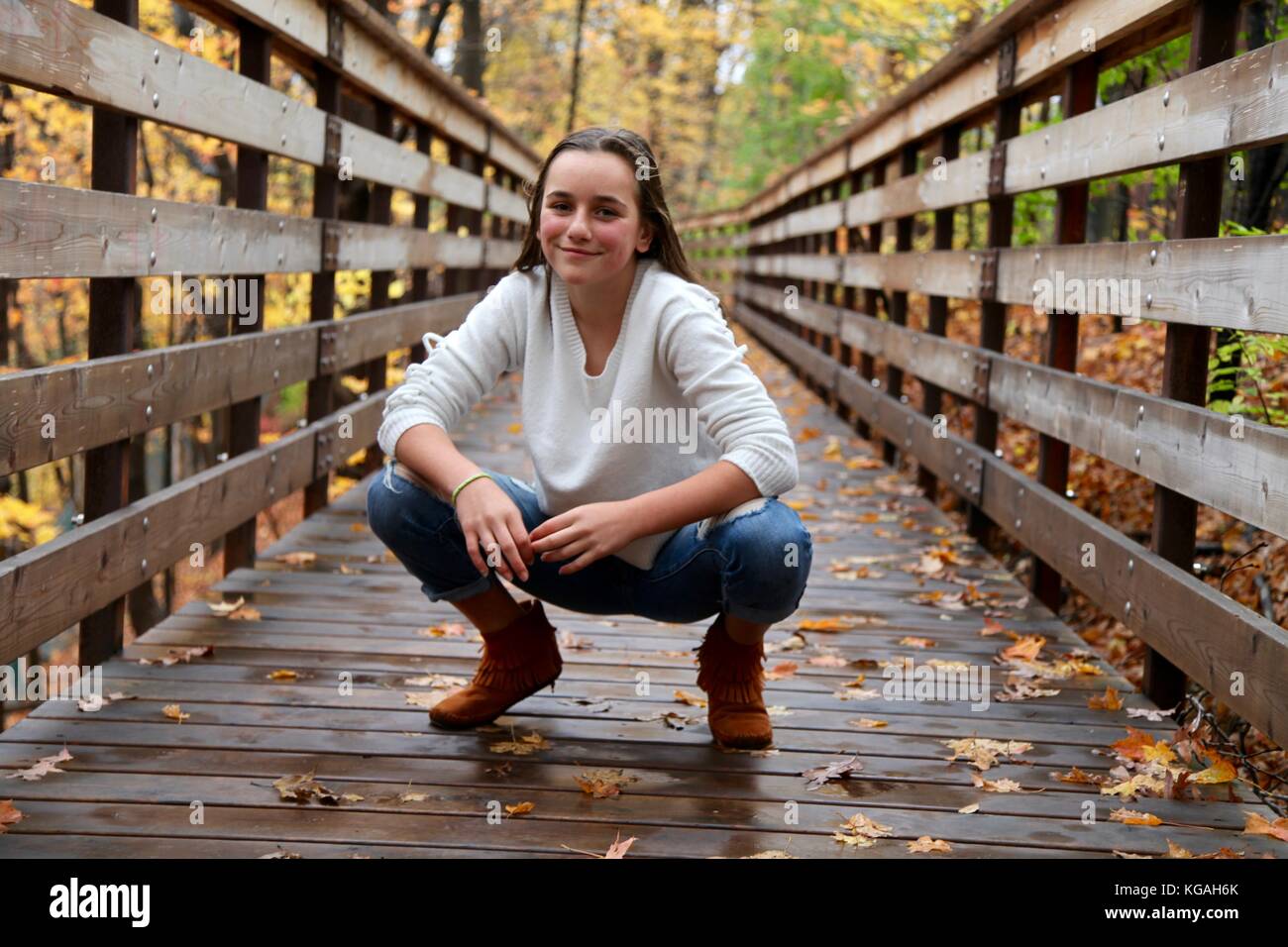 Portrait of a young teenage girl posing on a bridge in a forest during ...