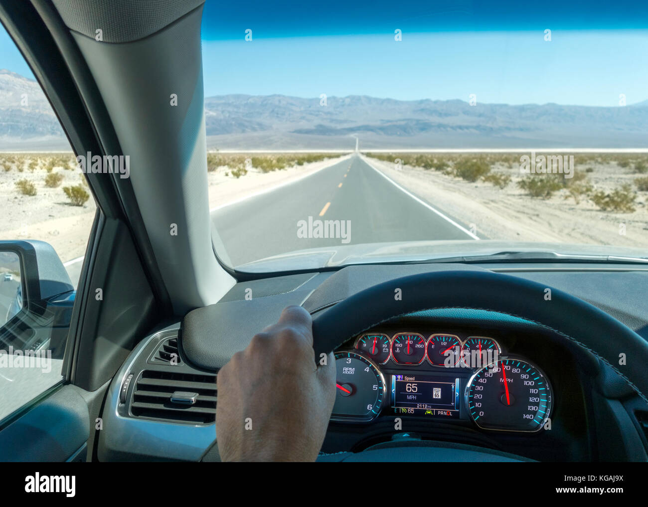 Death Valley Scenic Byway. Road trip driving point of view with dashboard and cruise control at 65mph. 65 mph speed limit on digital dashboard. Stock Photo