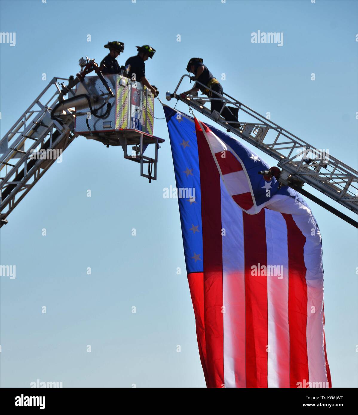Firemen hanging an American Flag between their fire trucks Stock Photo