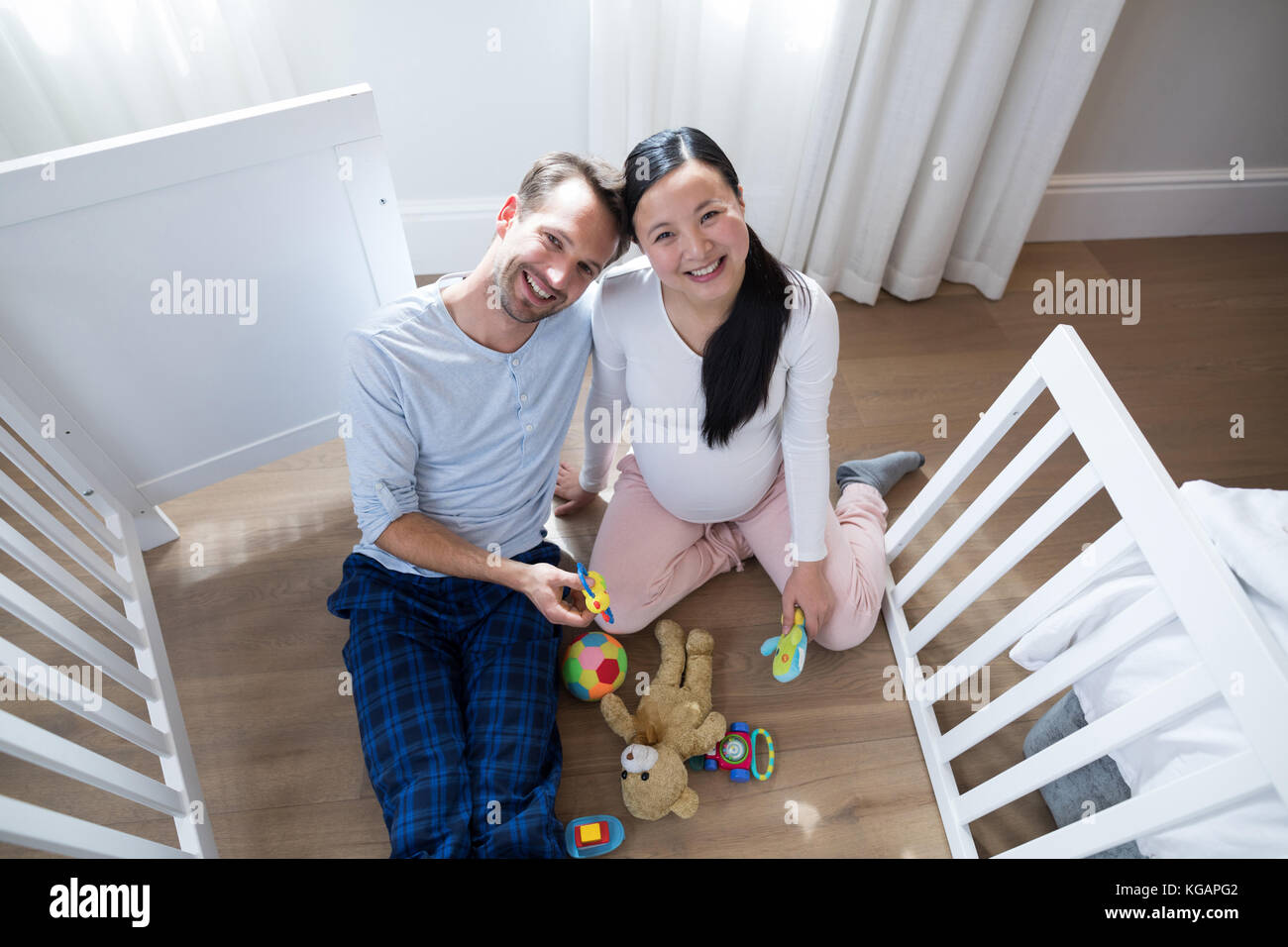 Overhead of happy couple playing with toys in bedroom Stock Photo