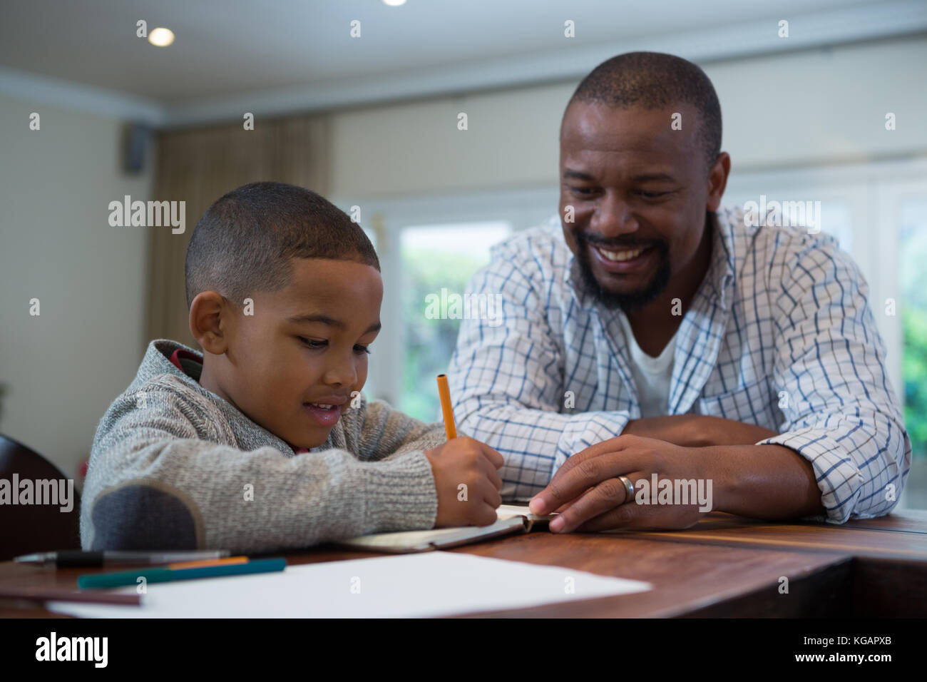 Father helping his son with homework in living room at home Stock Photo ...
