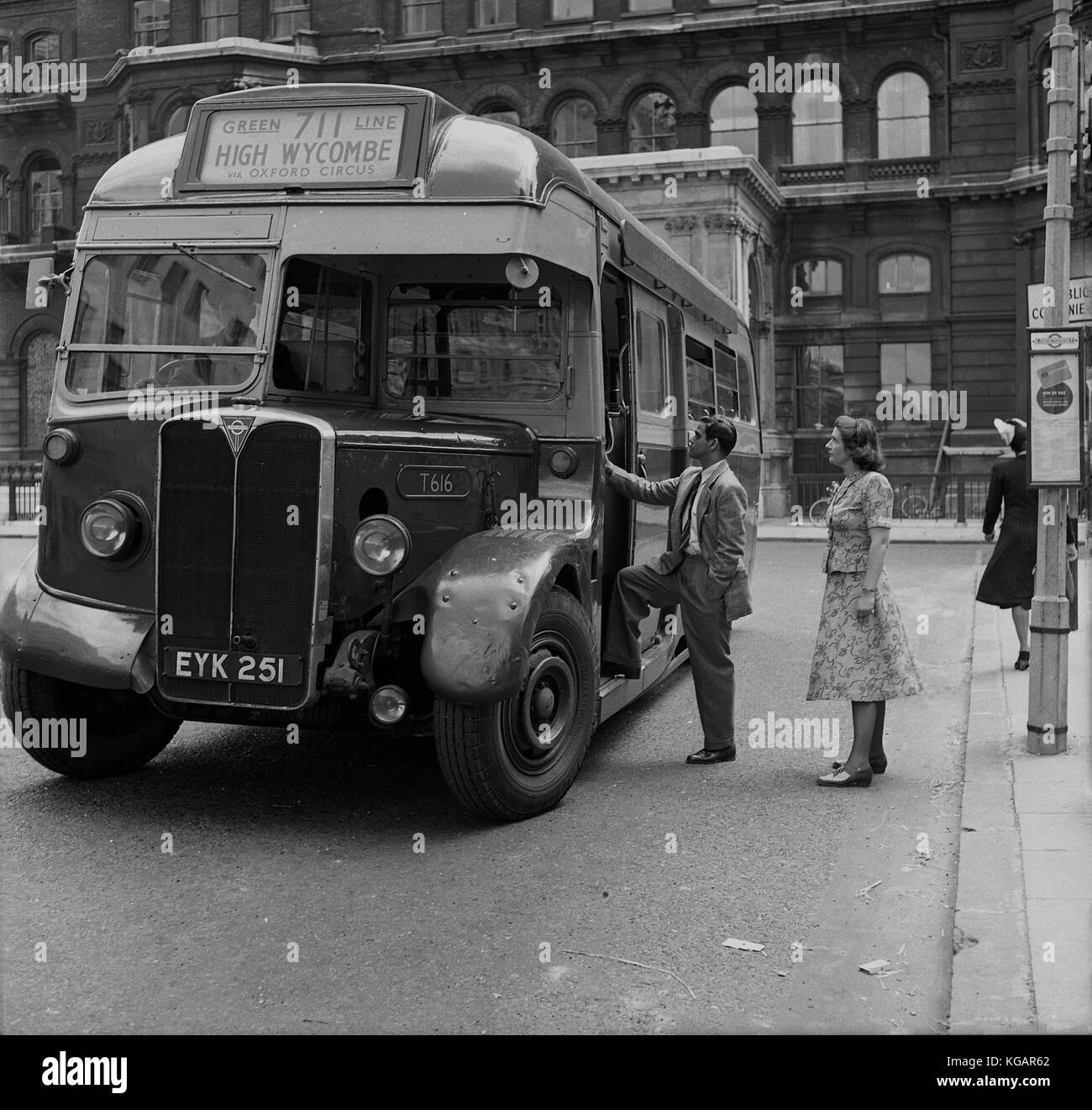 1950s, historical picture showing an overseas gentleman and a lady behind him at Charing Cross, Central London waiting to board the 711 Green Line bus, via Oxford Circus, to the county town of High Wycombe in Buckinghamshire, England, UK. Stock Photo