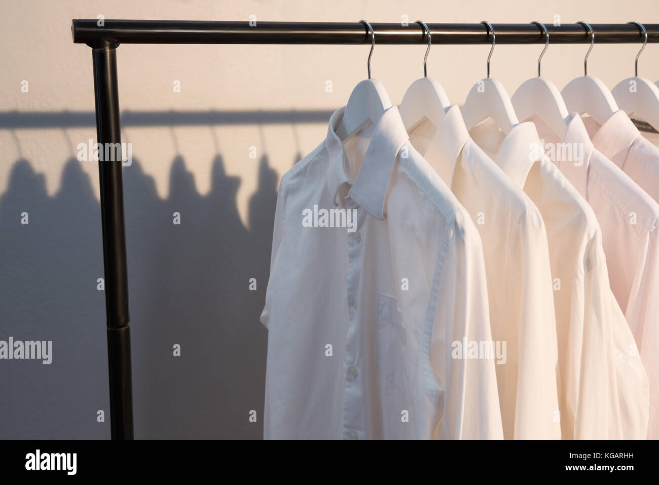 Shirts hanging on cloth hanger against wall Stock Photo - Alamy