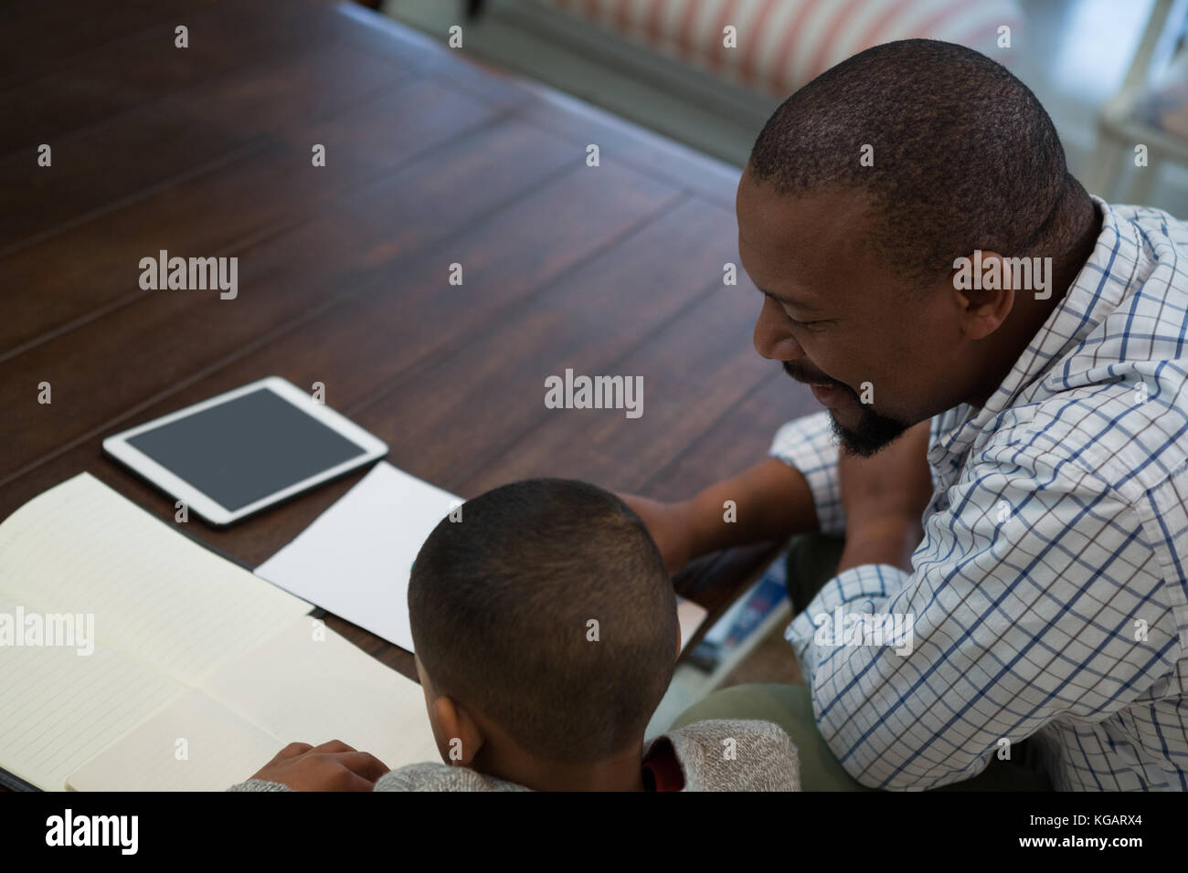 Father helping his son with homework in living room at home Stock Photo ...