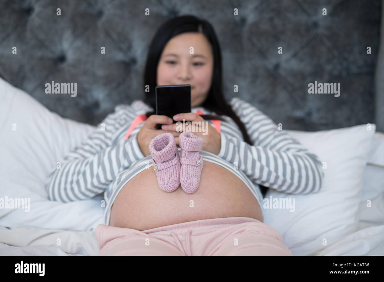 Pair of baby socks on pregnant woman stomach in bedroom Stock Photo