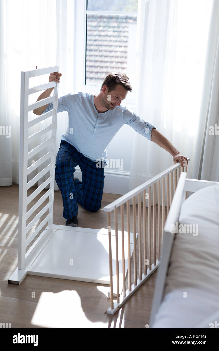 Attentive man making cot in bedroom Stock Photo