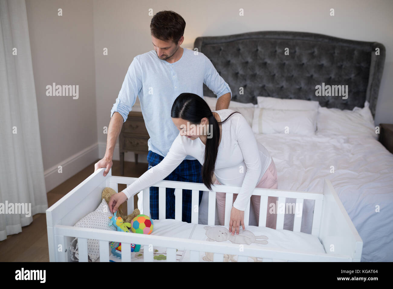 Couple arraigning toys in cot at home Stock Photo